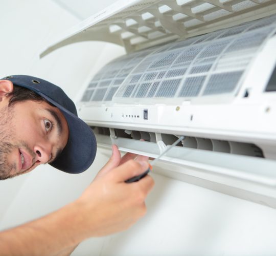 Serwisant z ADK Klimatyzacje Wrocław kończy montaż klimatyzatora ścienno-przysufitowego w mieszkaniu.